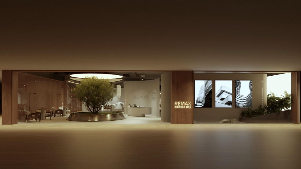 Projeto de loja: fachada de vidro à noite, com uma placa RE/MAX e o interior de madeira iluminado
